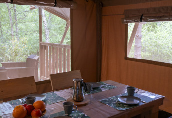 Inside view of Safari Lodge at Campsite Des Randonneurs, France, with set dining table and woodland view.
