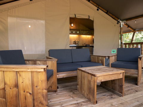 Houten meubels en gezellige zithoek in Safari Lodge LUXE tent op Camping Des Randonneurs, Frankrijk.
