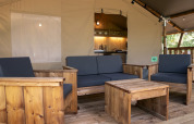 Arredi in legno e salotto accogliente nella tenda Safari Lodge LUXE al campeggio Des Randonneurs, Francia.