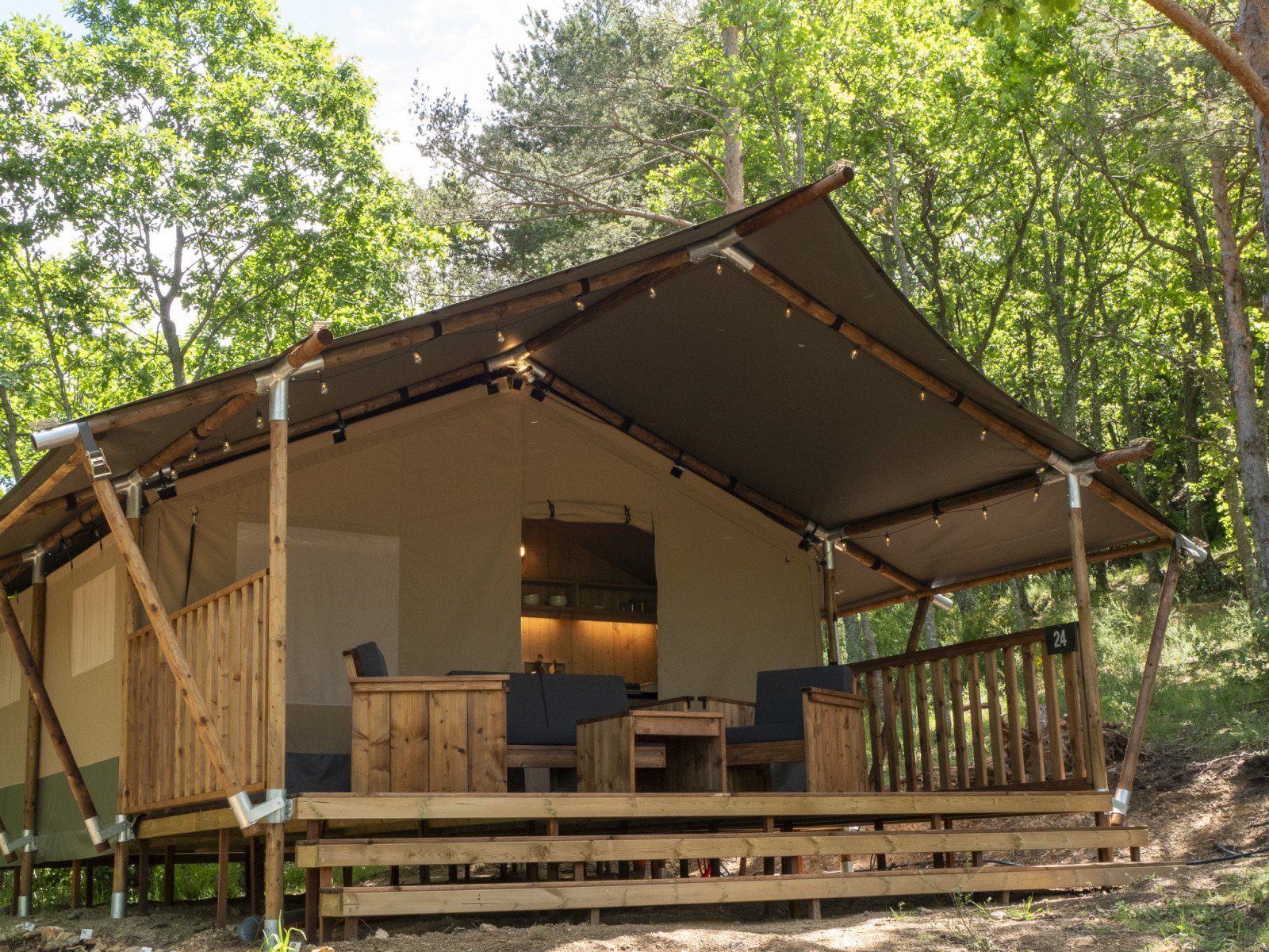 Safari Lodge LUXE safaritent met sanitaire voorzieningen, houten terras en zithoek in het bos.
