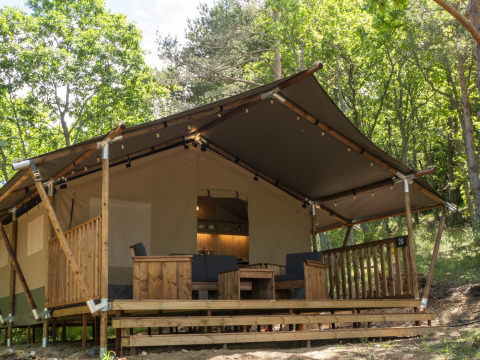 Safari Lodge LUXE safari tent with sanitary facilities, wooden terrace, and seating area in the forest.
