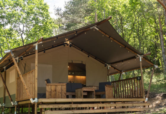 Safari Lodge LUXE safari tent with sanitary facilities, wooden terrace, and seating area in the forest.