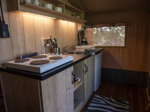 Keukenhoek in Safari Lodge LUXE tent op Camping Des Randonneurs in Frankrijk met fornuis en gootsteen.