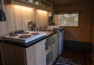 Keukenhoek in Safari Lodge LUXE tent op Camping Des Randonneurs in Frankrijk met fornuis en gootsteen.