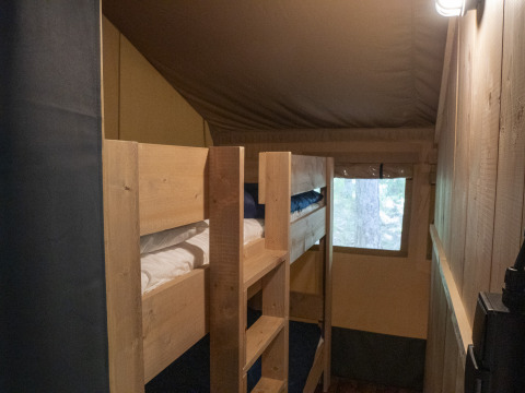 Interieur van de Safari Lodge LUXE tent op Camping Des Randonneurs in Frankrijk, met houten stapelbedden.