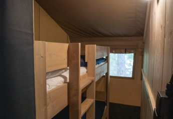 Interior view of Safari Lodge LUXE tent at Campsite Des Randonneurs, France, featuring wooden bunk beds.