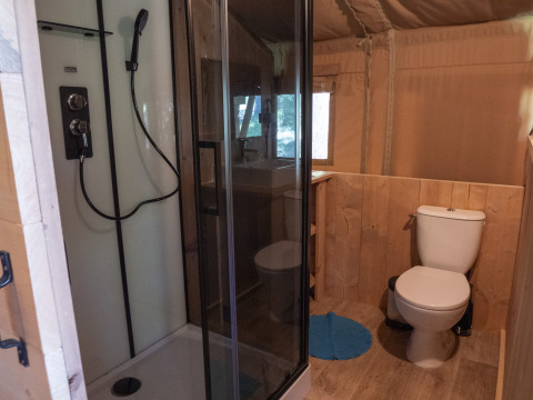 Bathroom inside Safari Lodge LUXE tent at Campsite Des Randonneurs in France with shower and toilet.