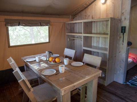 Interieur van de Safari Lodge LUXE tent op Camping Des Randonneurs in Frankrijk met eettafel.