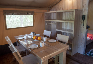 Interno della tenda Safari Lodge LUXE al campeggio Des Randonneurs in Francia con tavolo da pranzo.
