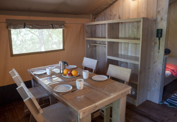 Interior of Safari Lodge LUXE tent at Campsite Des Randonneurs in France with dining table and wooden shelves.
