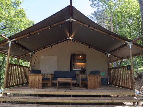 Safari Lodge LUXE tent op Camping Des Randonneurs in Frankrijk met houten veranda en zithoek buiten.