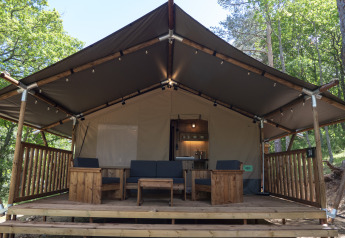 Safari Lodge LUXE tent at Campsite Des Randonneurs in France, featuring a wooden deck and outdoor seating.