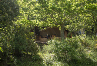 Safari Lodge LUXE tent op Camping Des Randonneurs in Frankrijk, verscholen tussen bomen en groene natuur.