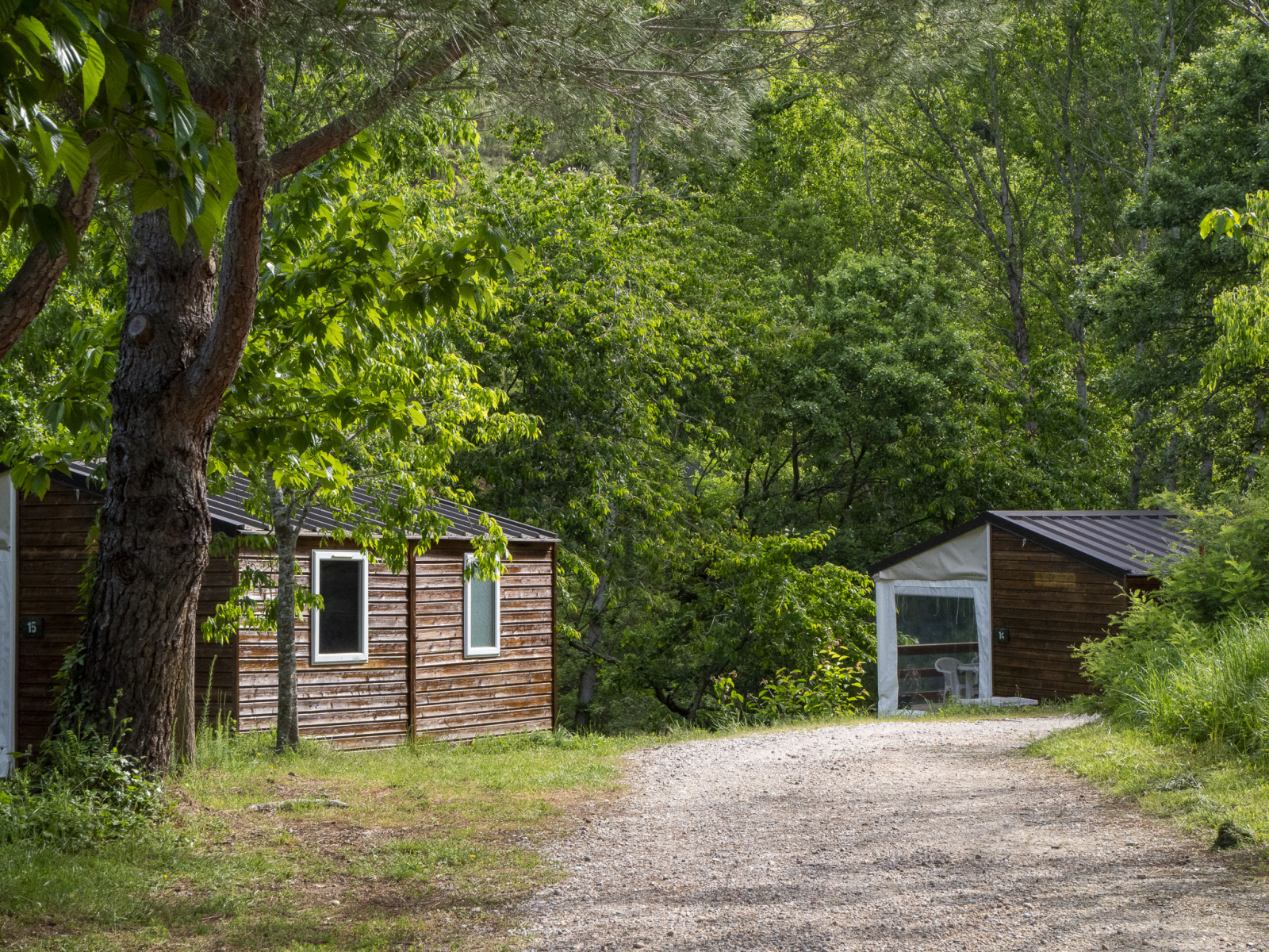 Grindpad bij Mobile Home Tithome op Camping Des Randonneurs, omgeven door groene bomen in Frankrijk.