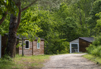 Schotterweg vor Mobile Home Tithome auf dem Campingplatz Des Randonneurs, umgeben von grünen Bäumen.