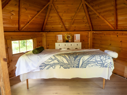 Innenaufnahme einer Holzhütte mit Massagetisch im Ferienpark Des Randonneurs in Okzitanien, Frankreich.