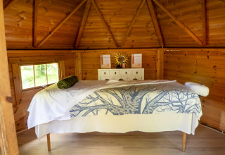 Vue intérieure d'une cabane en bois au camping Des Randonneurs, Occitanie, France, avec une table de massage.