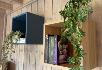 Mensole moderne con libri e piante nel Mobi Lodge presso Arden Parks Tulderheyde, Belgio.