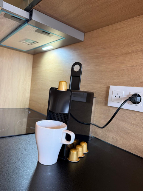 Koffiemachine met capsules en witte tas op Mobi Lodge aanrecht, Arden Parks Tulderheyde, België.