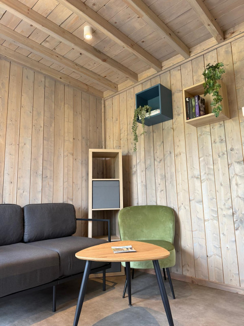 Lounge moderna presso Mobi Lodge ad Arden Parks Tulderheyde, Belgio, con divano e arredi in legno.