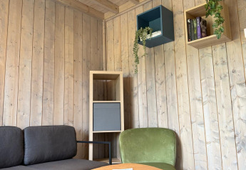Lounge moderna presso Mobi Lodge ad Arden Parks Tulderheyde, Belgio, con divano e arredi in legno.