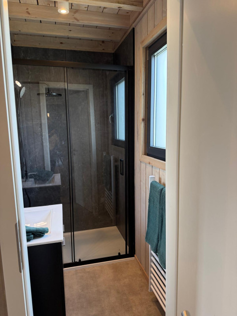 Bagno moderno nella Mobi Lodge ad Arden Parks Tulderheyde in Belgio, con doccia in vetro e pareti in legno.