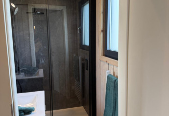 Bagno moderno nella Mobi Lodge ad Arden Parks Tulderheyde in Belgio, con doccia in vetro e pareti in legno.
