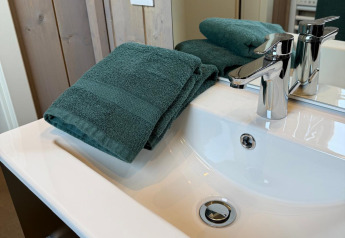 Lavandino con asciugamani verdi al Mobi Lodge, Arden Parks Tulderheyde, Belgio, bagno in legno.