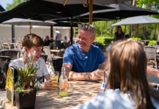 Family enjoying drinks outdoors at a café table in Holiday Park Molenvelden, North Brabant, Netherlands.