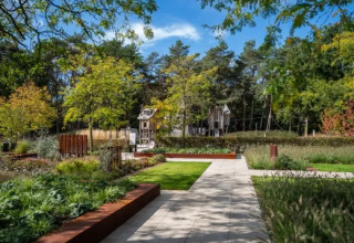 Sentiero in un giardino verde nel parco vacanze Molenvelden, Brabante Settentrionale, Paesi Bassi, alberi visibili.