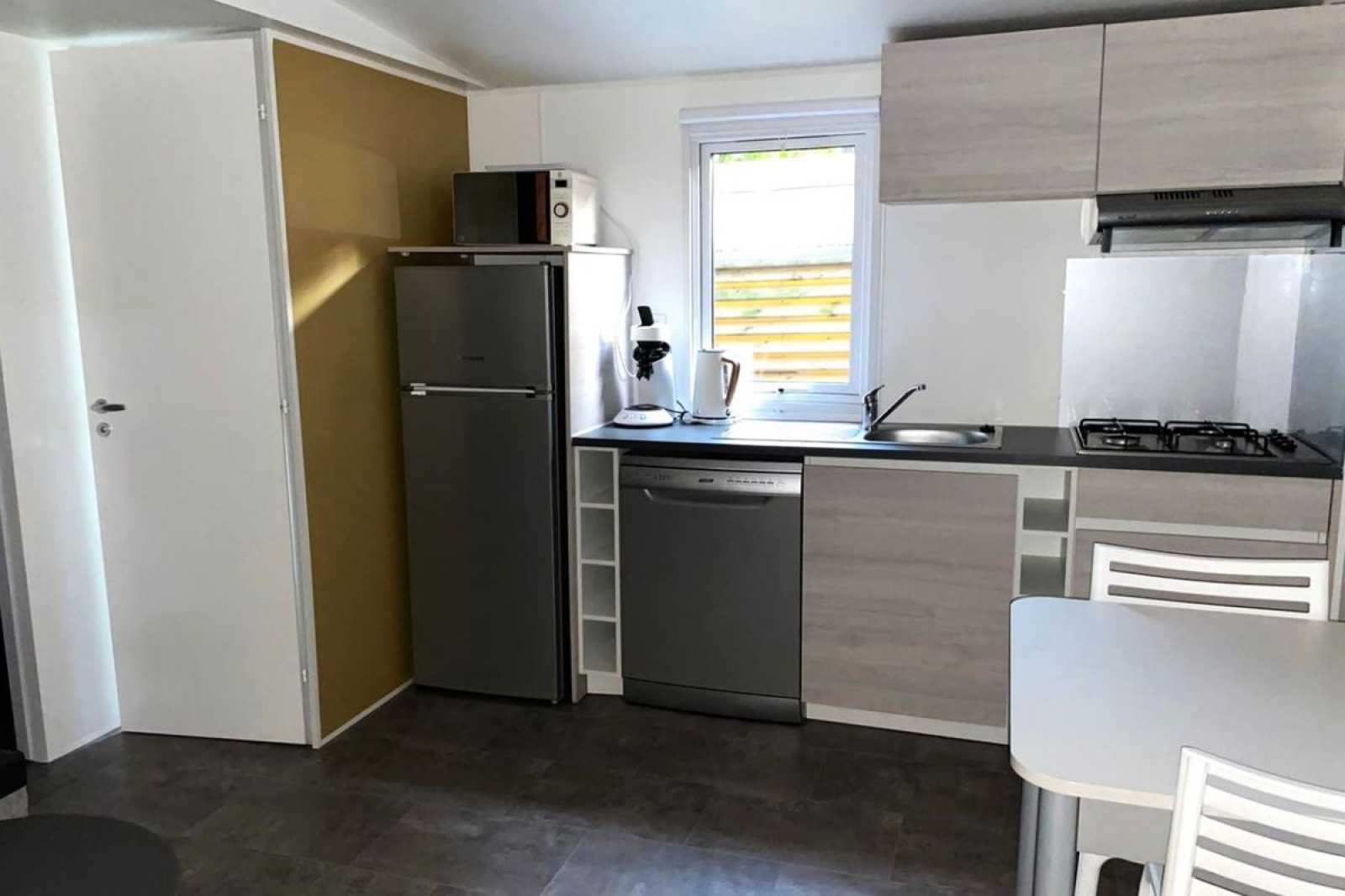 Moderne kitchenette in Comfort Mobile Home op Camping Paradis Family des Issoux met koelkast, vaatwasser en eethoek.