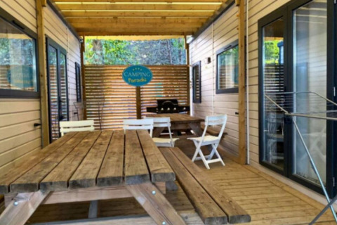 Ruime houten veranda met tafels bij De Familie - 2 Stacaravans, Camping Paradis Family des Issoux in Frankrijk.