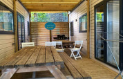 Terraza de madera con mesas y sillas en De Familie - 2 Stacaravans, Camping Paradis Family des Issoux en Francia.
