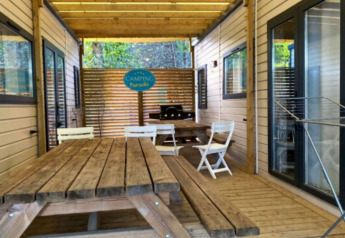 Udendørs træterrasse med borde og stole ved De Familie - 2 Stacaravans på Camping Paradis Family des Issoux.