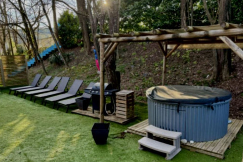 Buitenruimte met ligzetels, overdekte jacuzzi en barbecue bij Paradijs Luxe Stacaravan in Frankrijk.
