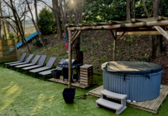 Udendørs afslapningsområde med liggestole, overdækket jacuzzi og grill ved Paradijs Luxe Stacaravan i Frankrig.