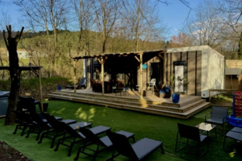 Buitenruimte met ligstoelen, terras en luxe stacaravan met jacuzzi op Camping Paradis Family des Issoux, Frankrijk.