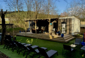 Udendørsområde med liggestole, terrasse og luksusstacaravan i Paradijs med jacuzzi på Camping Paradis Family des Issoux, Frankrig.