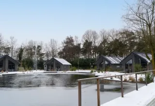 Cabañas vacacionales cubiertas de nieve junto a un lago en el parque Latour, North-Brabant, Países Bajos.