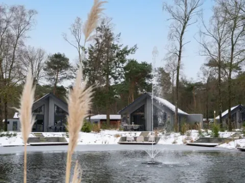 Winterliches Ferienparkbild vom Holiday park Latour, Nordbrabant, Niederlande, mit Teich und Hütten.