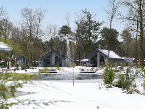 Holiday park Latour in North Brabant, Netherlands, with snow-covered cabins and a central pond.