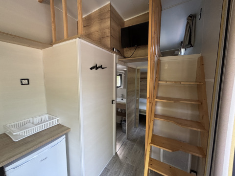 Indvendig udsigt over Tiny House ved Recreation Park de Paalberg med trappe, tekøkken og loftsområde.