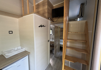 Vue intérieure du Tiny House au Recreation Park de Paalberg, escalier en bois, TV et kitchenette.