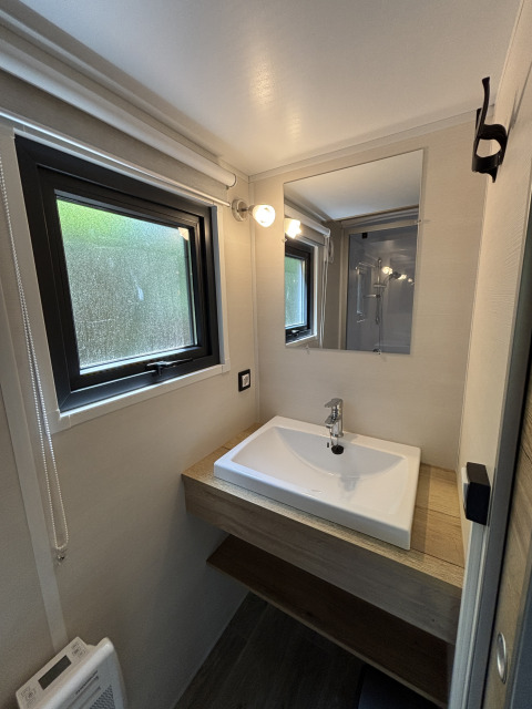 Moderne, kompakt håndvask og spejl på badeværelset i Tiny House ved Recreation Park de Paalberg, Holland.