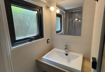 Salle de bain moderne et compacte avec lavabo et miroir au Tiny House du Recreation Park de Paalberg, Pays-Bas.
