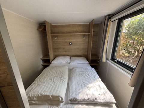 Et lille soveværelse i Tiny House på Recreation Park de Paalberg, Holland, med dobbeltseng og vindue.
