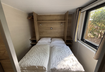 Petite chambre du Tiny House au Parc de loisirs De Paalberg, Pays-Bas, avec lit double et grande fenêtre.