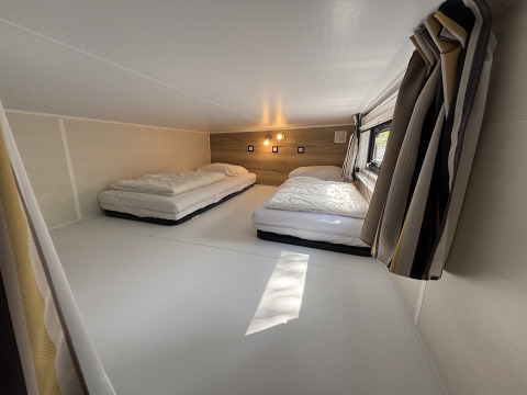 Moderne loftsoveplads med to lave senge og vindue på Tiny House ved Recreation Park de Paalberg, Holland.