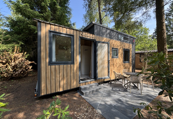 Lille træhus med terrasse og havemøbler i skoven, Tiny House ved Rekreationspark de Paalberg, Holland.