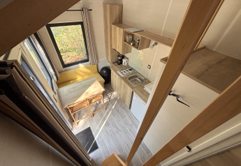 Vista dall'alto di una tiny house con cucina, tavolo da pranzo e finestre al Recreation Park de Paalberg.